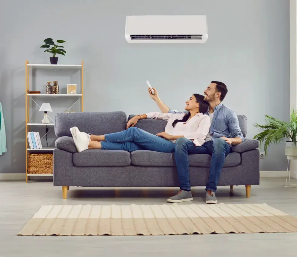 Man and woman relaxing on a couch in a cool room with well-maintained AC.