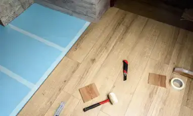 Worker repairing damaged wooden floor using professional tools